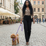 Woman walking a tiny brown toy poodle in a Lavender EcoBark Step-In Dog Harness and matching leash on a historic cobblestone street in Europe.