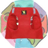 A stack of colorful EcoBark breathable mesh step-in dog harnesses, featuring a bright cherry red harness prominently in the front with various other solid colors and fun patterns stacked behind it.